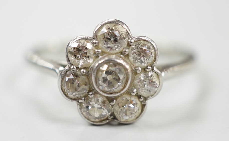 A 1920's 18ct, plat and millegrain set diamond flower head cluster ring, size O, gross weight 2.2 grams.